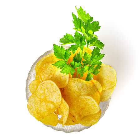 Potato chips with parsley flavor in a transparent glass bowl isolated on white background, top view.の写真素材