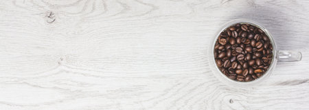 Banner with roasted coffee beans. Place for your text and label. Coffee beans are poured from a glass cup. Light brown background. Advertising layout for a coffee shop. Top view, flat lay. Copy space.の写真素材