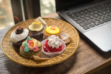 Laptop and cupcakes on wood table.の写真素材