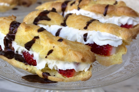 Strawberry eclair fille with wiped cream on the plate stand