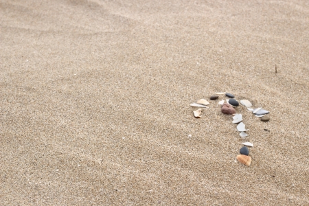 Arrow made on the beach with shells and stonesの写真素材