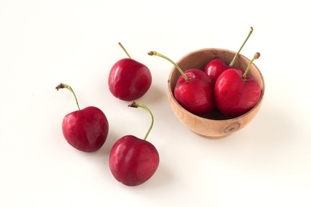 Cherries in small wodel bowl isolated on white backgroundの写真素材