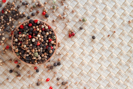 A wood bowl of mixed pepper and red dry berries on brown background. Photo is taken upwards, bowl is located on the up left corner.の写真素材