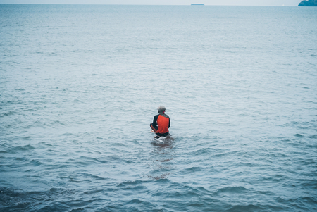 Man fishing seat on a stone patiently waiting at the seaの写真素材