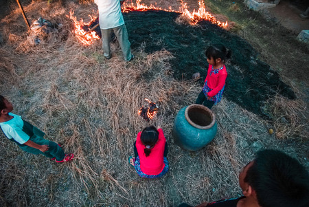 kids helping man burn the dead grassの写真素材