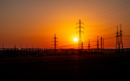 high-tension wires in sunset, high voltage, sunset, sunset behind power stationの写真素材