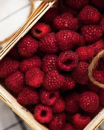 a lot of ripe raspberries in a wicker basket