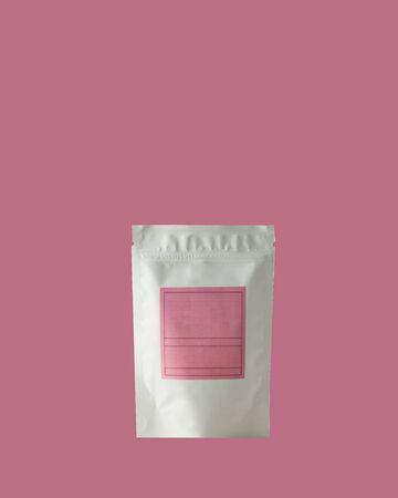 Aluminum bag for tea, coffee, condiments and other bulk substances with pink label for signature on pink background close-up. Tea bag isolated on pink background.の写真素材