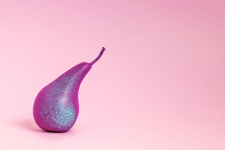 Bright purple pear close-up on a pink background. Horizontal photo, lots of space for text on the right. Creative minimalistic concept.の写真素材