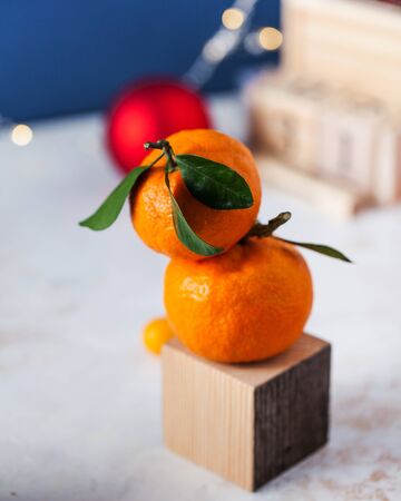 Tangerines with green twigs and leaves close-up on a Christmas background with Christmas toys. The background is a classic blue color according to the 2020 trend.の写真素材