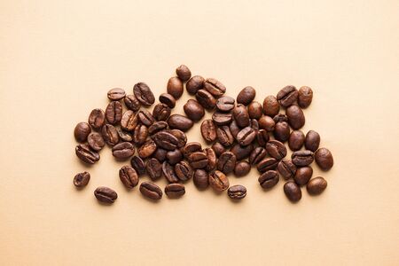 A handful of arabica coffee beans on a light background. Horizontal photo for coffee houses, screensavers, roastersの写真素材