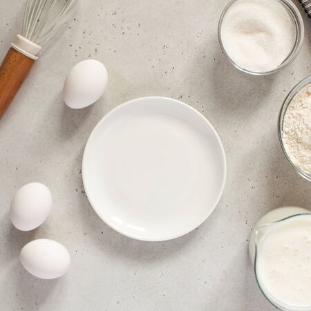  Ingredients for baking with flour and a cooking whisk with an empty white plate. The concept of...