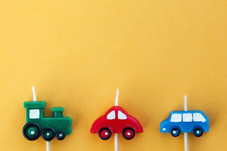 Multi-colored candle cars on a yellow background with space for text. The concept of children's holiday, International Children's Day. Horizontal photo.の写真素材