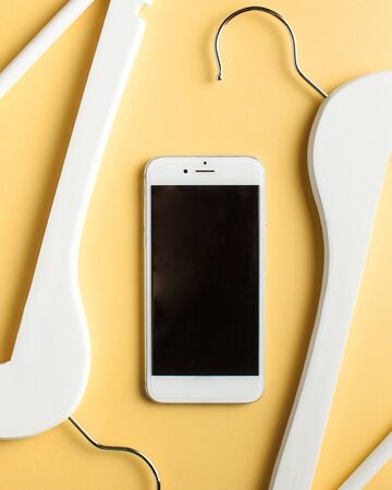  Online shopping concept. mobile phone and clothes hanger on a yellow background. Copy space. の写真素材