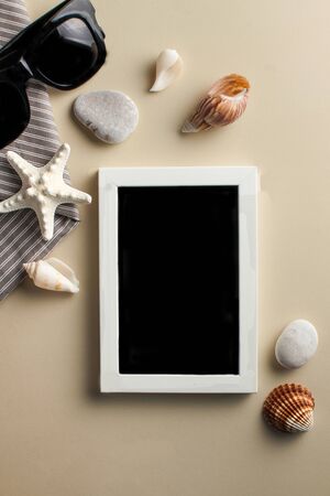  Tropical background. Flatlay with empty white photo frame with starfish, sunglasses and shells on a colored background. The concept of travel, vacation at sea. Copy spaceの写真素材