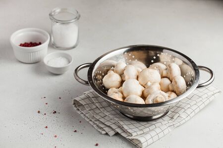 Fresh champignon porcini mushrooms in a metal colander, spices in bowls. Food for vegetarians. Copy space. horizontal photoの写真素材