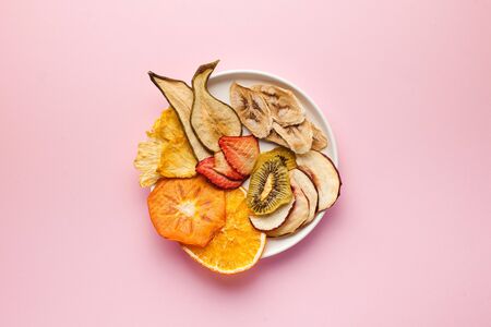  Dried fruit chips on a pink background. The concept of a healthy snack without sugar, dessert for...