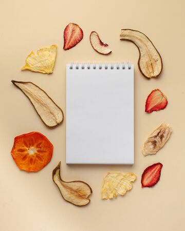 Blank notebook for text, fruit chips. The concept of a healthy diet, vegetarian food, fruit desserts without sugar.Copy space. Flatlayの写真素材