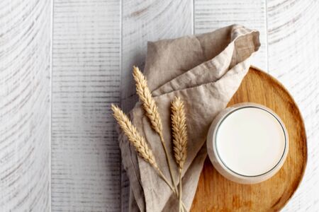 Glass of milk on a wooden plate and spikelets of wheat. The concept of organic, farm products. Copy space. High quality photoの写真素材