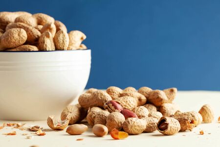 A handful of peanuts in shells and in a bowl. The concept of a healthy diet, a snack for...