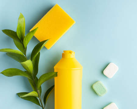 Liquid dishwashing liquid, dishwasher tablets on a blue background. Means for washing dishes. Copy...