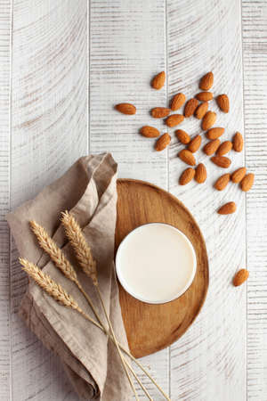 Almond vegan milk in a glass and almond nuts on a light background. Alternative to dairy products. Copy space. Flatlay. High quality photoの写真素材