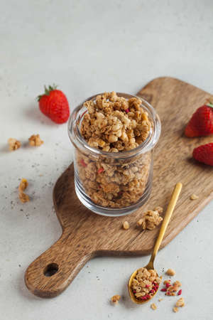 Homemade granola in a glass jar with fresh strawberries. The concept of a quick Breakfast, a healthy...