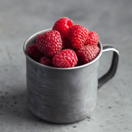 Fresh ripe raspberries in a wooden bowl on a gray background. The concept of healthy eating. Copy...