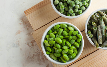 Frozen vegetables such as green peas, soy, green beans, and baby food in white bowls with copy space. Healthy food, frozen food. High quality photoの写真素材