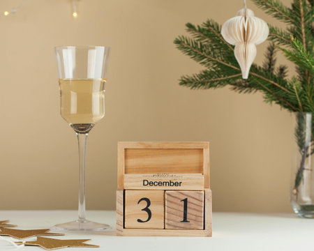 Wooden calendar December 31. New year, Christmas background. A glass of wine, a tree branch, a...