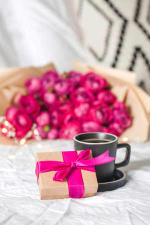 Coffee mug in bed on the background of a bouquet of flowers and a gift. Concept of Valentine's day, March 8, mother's day and gift for a woman.y and gift for a woman. High quality photoの写真素材