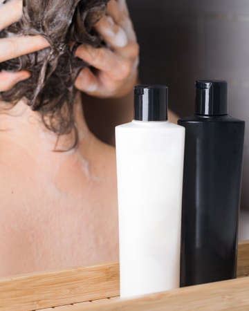 Shampoo, hair conditioner with a place for a logo on the background of a girl who washes her hair. Concept of hair care.の写真素材