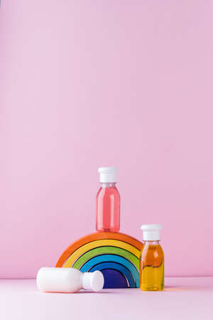 Baby detergents on a toy rainbow on a pink background. The concept of baby skin care. Copy space.の写真素材