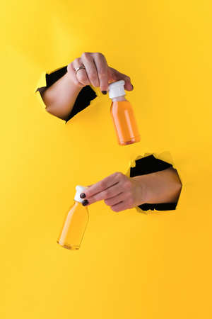 The womans hands hold tubes of shower gel. Daily cosmetic product. Empty space for text or logo.の写真素材