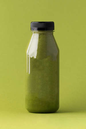 Green smoothie in a bottle on a green background. The concept of healthy eating. Copy space.の写真素材
