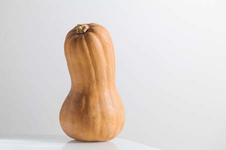 Pumpkin on the table on a light background. Minimalism, trendy food photo. Copy space.