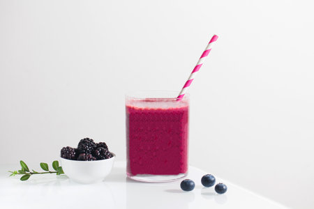 Berry smoothie in a glass with a straw and blueberries and blackberries. Detox, healthy eating.の写真素材