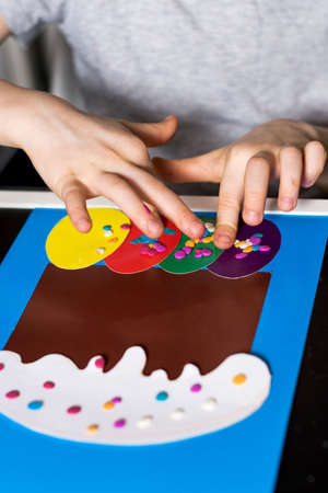 The boy makes an Easter card with his own hands, an Easter cake and Easter eggs from paper.の写真素材