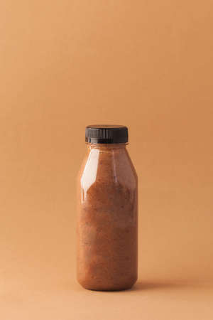 Brown smoothies in a bottle on a brown background. Sports nutrition, healthy food. Copy space.の写真素材