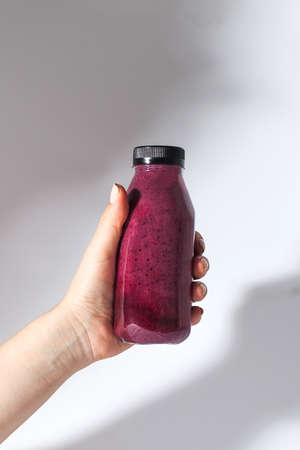 Berry smoothie in a bottle in the hand of a woman. Detox, healthy eating.