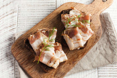 Ukrainian lard, pork lard, sprinkled with fresh chopped herbs on a wooden board. Copy space.