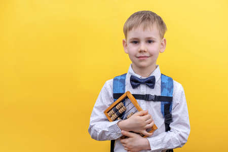 Cute little boy in uniform with backpack looking at camera while going to school for first time on 1...