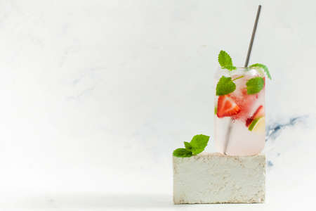 A refreshing summer drink with strawberries, lemon and mint in a glass on a light background. Strawberry lemonadeの写真素材
