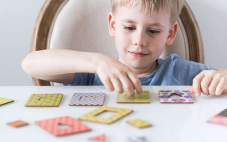The cute blonde boy is playing with a logical wooden toy. The Maria Montessori method. Wooden...