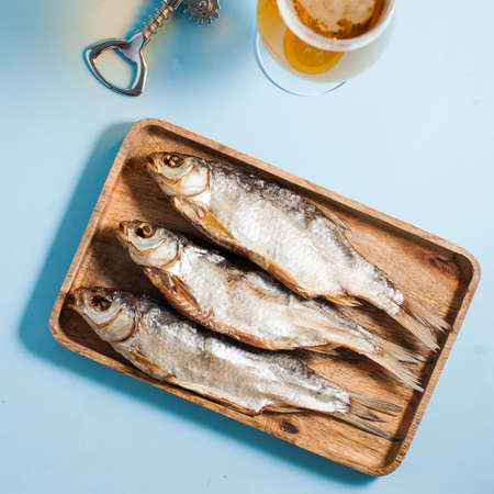Dried salted fish on a wooden tray. A delicious snack for beer.
