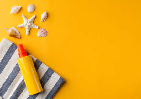Summer background. Seashells, sunscreen on a yellow background. Copy space.