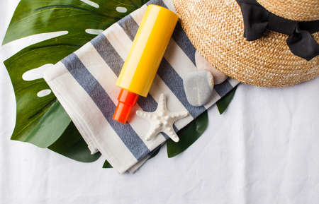 Summer background. Hat, seashells, sunscreen on a white towel. Copy space.の写真素材