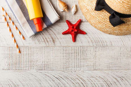 Summer background. Hat, seashells, sunscreen on a wooden background. Copy space.の写真素材