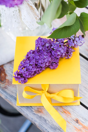 Gift box with yellow ribbon and lilac bouquets. A greeting card.の写真素材
