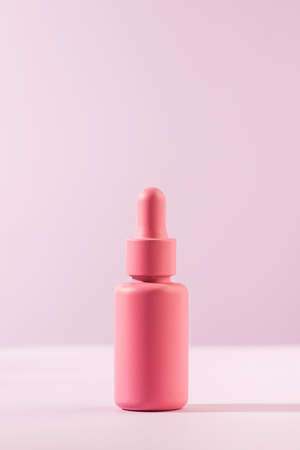 A mockup of a pink dropper with a facial serum on a pink background. Trends in facial skin care. Copy space.の写真素材